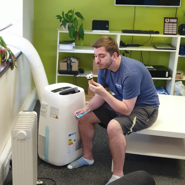 Technician sat eating an ice-cream next to an air-conditioning unit