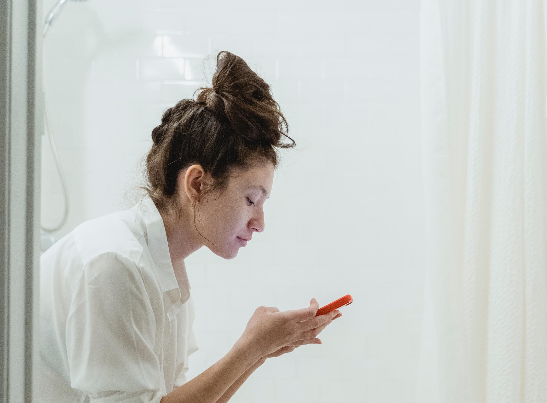 Side view of a woman sat looking intently at her phone